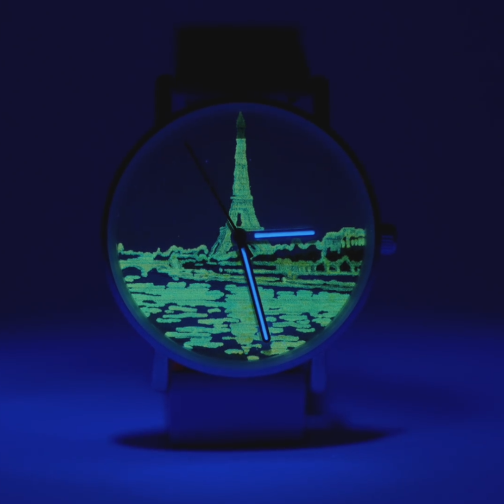 Das Ziffernblatt einer Uhr, mit einem fluoreszierenden Aufdruck des Eifelturms